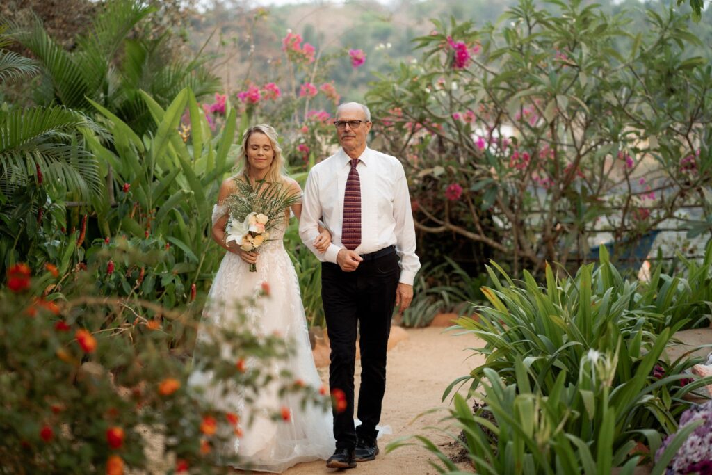 Bride Walking Down the Aisle with Her Father at Kala Bahia Bride walking down the bougainvillea-lined aisle with her father at Kala Bahia, a beachside wedding venue in South Goa near Palolem Beach.
