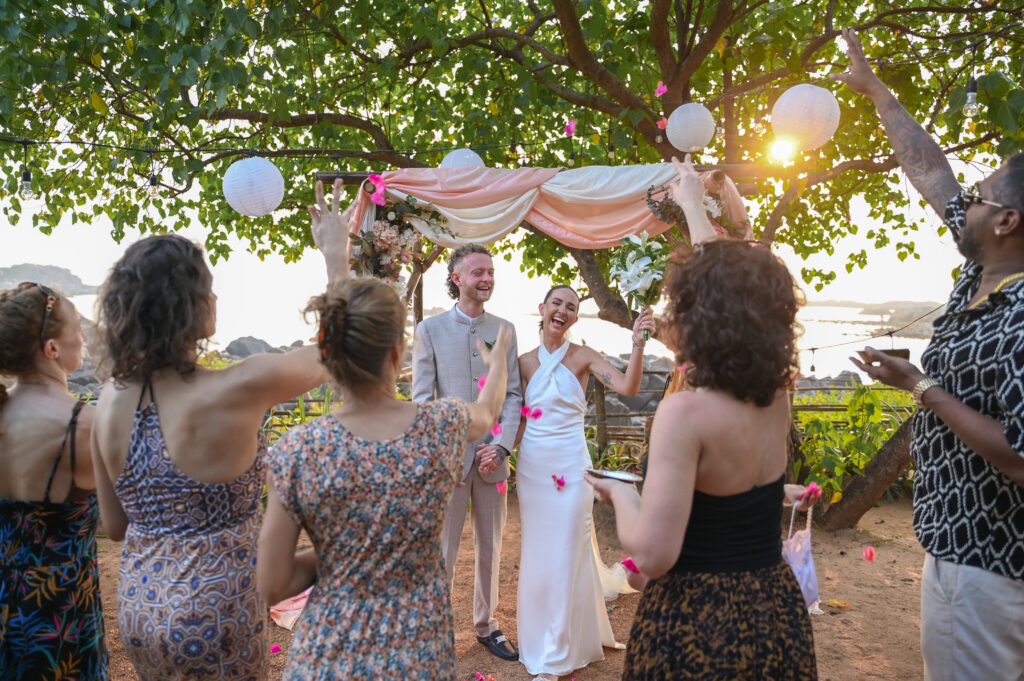 Rebecca & Regan Just Married Celebration at Kala Bahia Newlyweds Rebecca and Regan celebrating after their vows with guests showering them with petals at Kala Bahia, a stunning beachside wedding venue in South Goa near Palolem Beach.